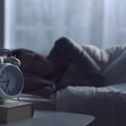 目覚まし時計をかけて眠る女性