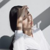 顔に手をかざし目を閉じる女性