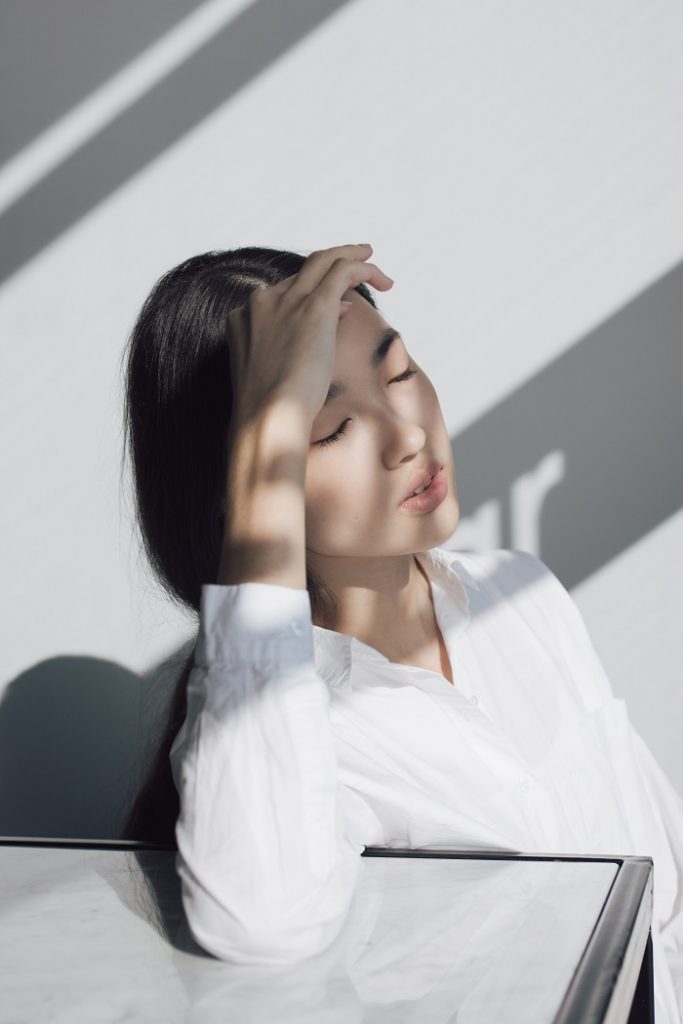 顔に手をかざし目を閉じる女性