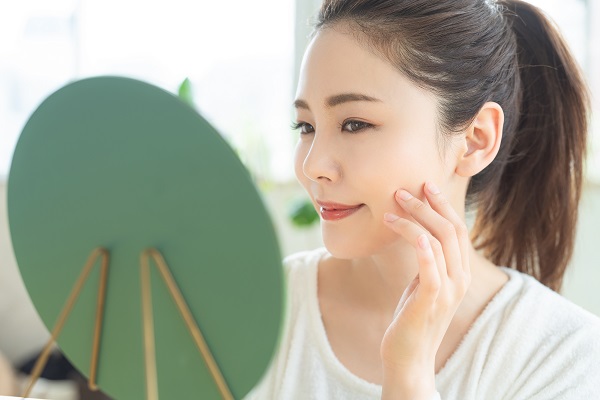 鏡を見てほほ笑む女性