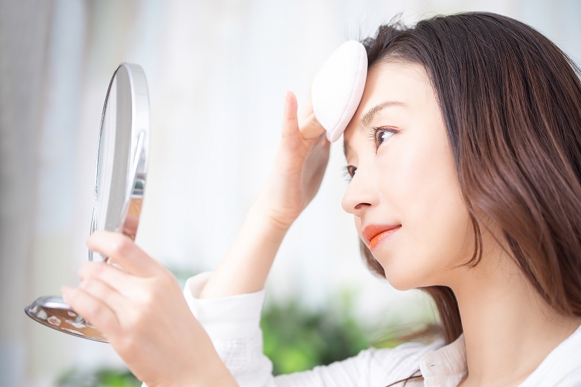 鏡を見てメイク直しをする女性
