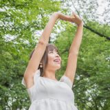 木に囲まれた場所で伸びをする女性