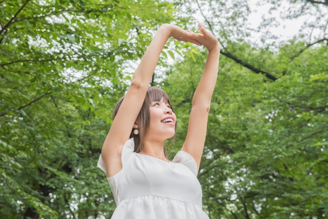 木に囲まれた場所で伸びをする女性