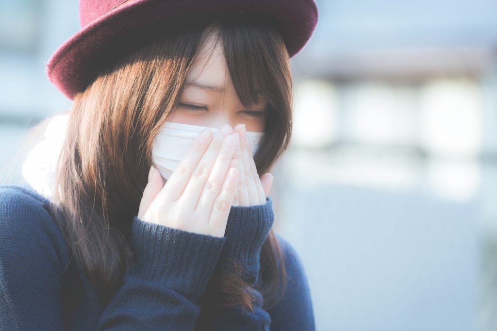 マスクの上から手を当てる女性
