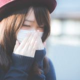 マスクの上から手を当てる女性