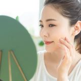 鏡を見ながら肌に触れる女性