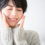 暖かそうなニットを着用し、目を閉じて嬉しそうな表情をした女性