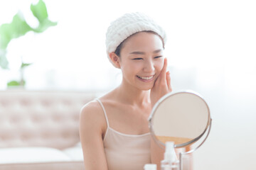 頬に手を当て、鏡を見ながら微笑む女性
