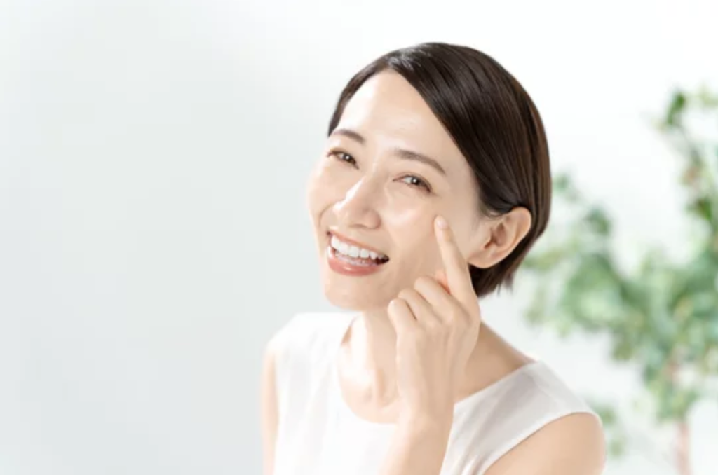 笑顔で目元に触れる女性