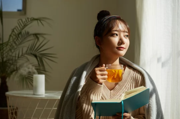 本を持ちながらお茶を飲んでいる女性