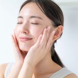 頬に触れ、微笑む女性