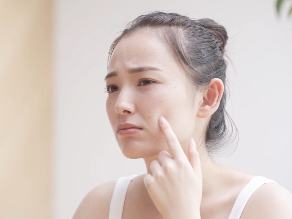 頬に指を置いて困っている女性
