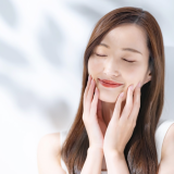 微笑みながら顔に手を触れる女性