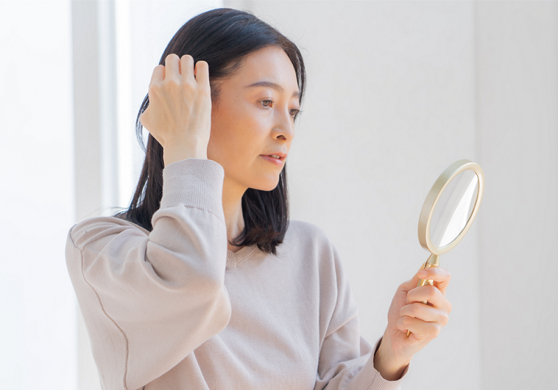 鏡を見ながら髪を耳にかける女性