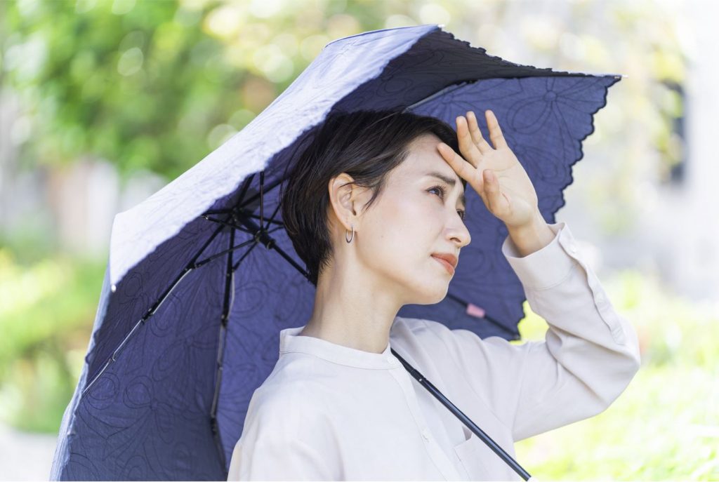 日傘をさして暑そうにしている女性